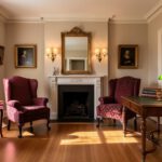 Symmetrical traditional living room with wingback chairs, a fireplace, damask drapes, and warm wood accents in cream, brown, burgundy, and gold tones.
